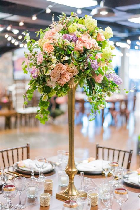 A Tall Vase Filled With Pink And Green Flowers On Top Of A Wooden