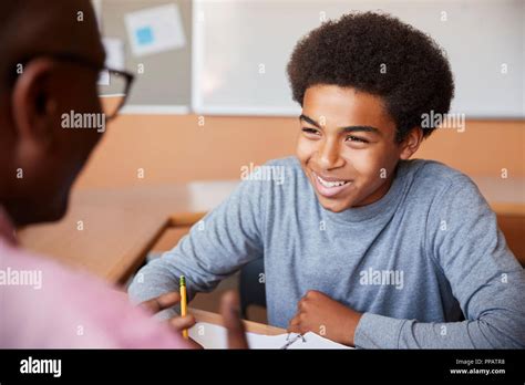 High School Tutor Giving Male Student One To One Tuition At Desk Stock