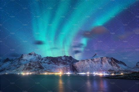 An Aurora Bore Over The Mountains And Water At Night With Lights In The