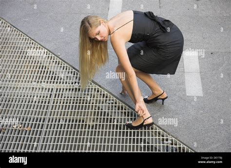 Young Woman With Her High Heeled Shoe Stuck In A Pavement Drain Cover