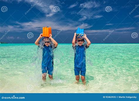 Twin Brothers On Tropical Holidays Having Fun Pouring Water Over Stock