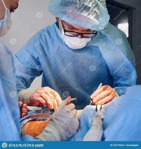 Doctor And Assistant Doing Abdominoplasty Surgery In Modern Clinic