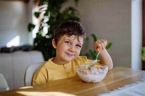 Das Porträt eines lächelnden Jungen der zu Hause in der Küche sein Frühstück genießt