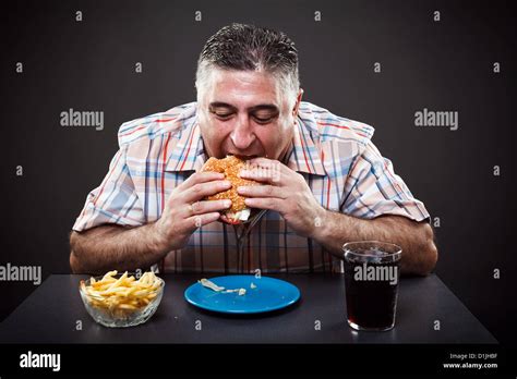 Portrait Of A Greedy Fat Man Eating Burger On Gray Background Stock