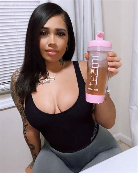A Woman Holding A Shaker Bottle In Her Right Hand And Posing For The Camera