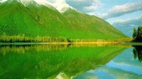 Green Covered Mountain With Reflection On River Under Blue Cloudy Sky