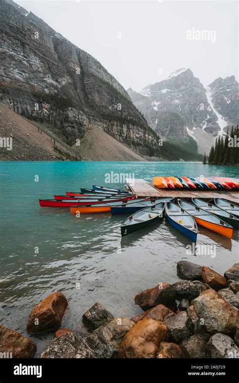 Colorful Canoes At Dock On Moraine Lake With Mountains In Background