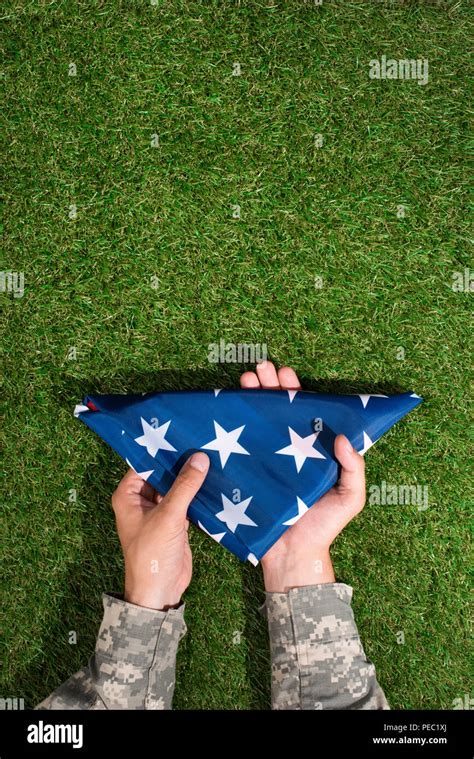 Partial View Of Soldier In Military Uniform Holding Folded Flag In