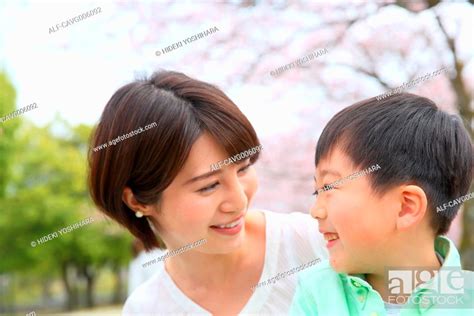 Japanese Mother And Son With Cherry Blossoms In A City Park Stock
