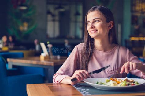 Young Woman Smiling And Looking Away While Eating Lunch At The