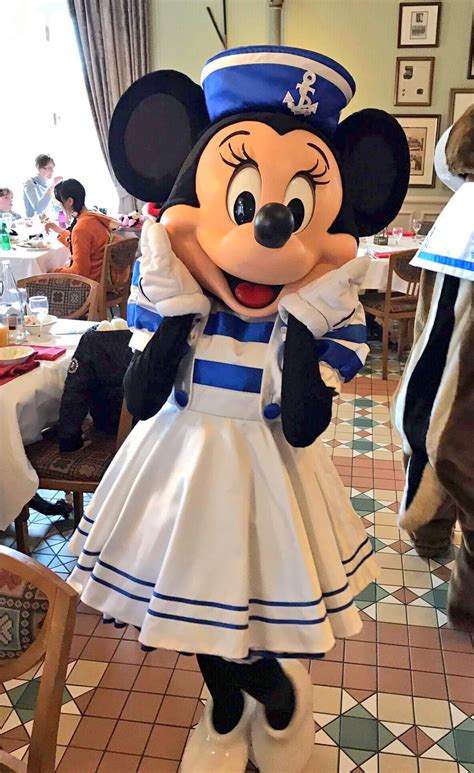 A Minnie Mouse Dressed In A Dress And Hat Standing On A Tiled Floor