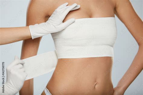 Plastic Surgery Doctor Hands Wrapping Female Breast In Bandage Stock