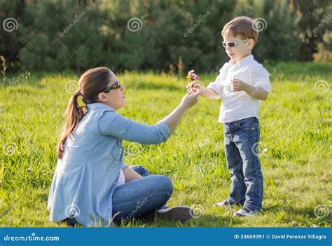 Hijo Que Da Un Ramo De Flores A Su Madre Embarazada En Un Campo Imagen