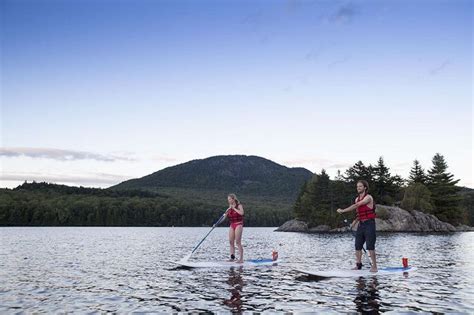 Two People Stand On Paddle Boards In The Water