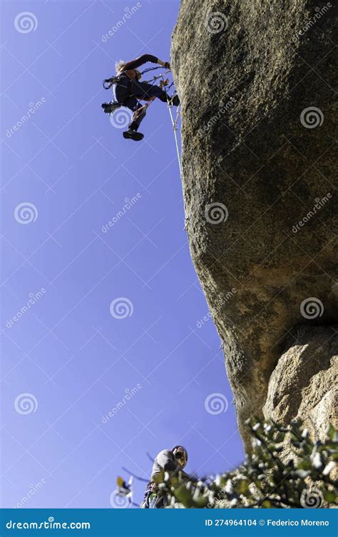 Two Young Adults Working Together To Climb A Granite Wall Rock