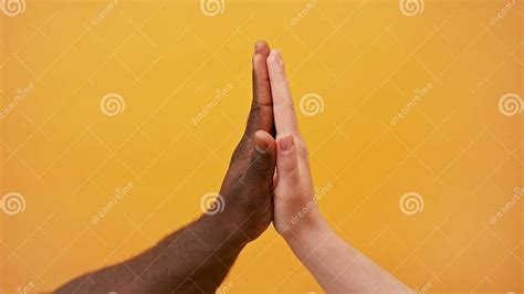 Black And White Hands Holding Together On The Orange Background Close