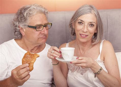 Pretty Mature Couple Having Fun In The Bed While Eating Breakfast Stock