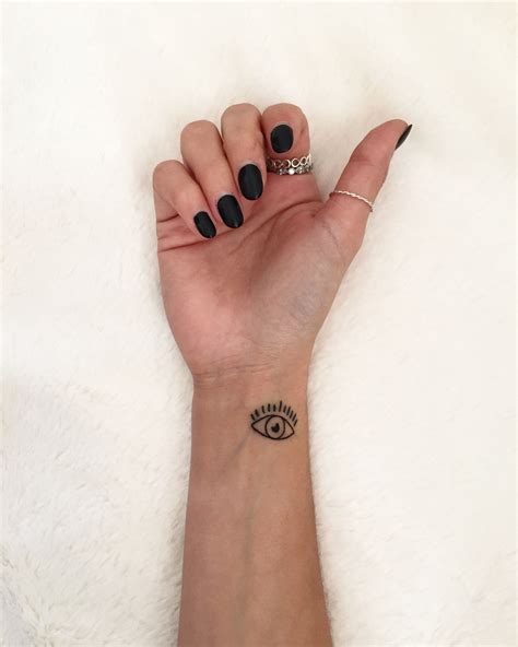 A Womans Hand With Black Nail Polish And An Eye Tattoo On Her Wrist