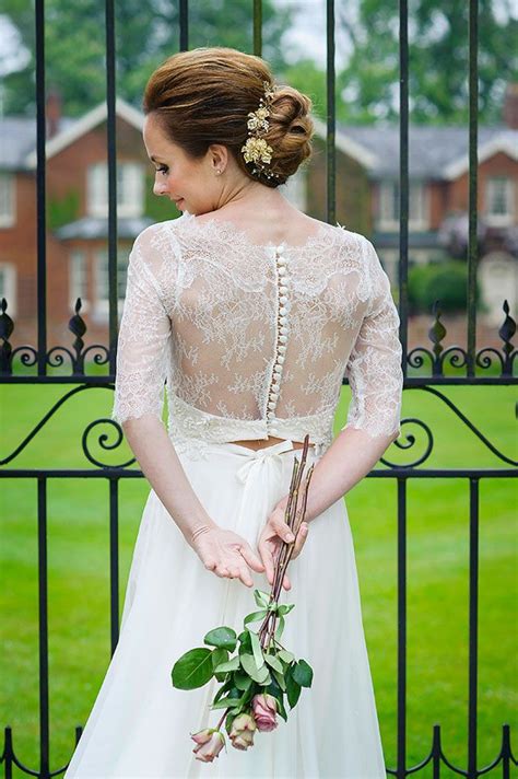 A Woman Standing In Front Of A Gate Wearing A Wedding Dress And Holding