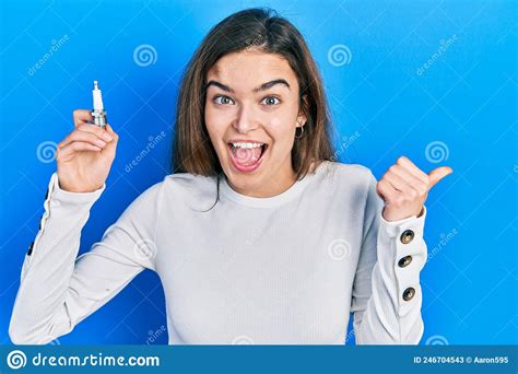 Young Caucasian Girl Holding Spark Plug Pointing Thumb Up To The Side