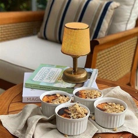 Three Bowls Of Oatmeal Sit On A Table Next To A Book And Lamp