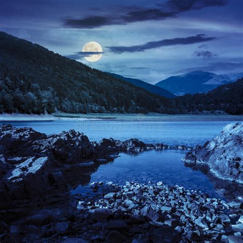 Lake Shore With Stones Near Pine Forest On Mountain At Night Stock