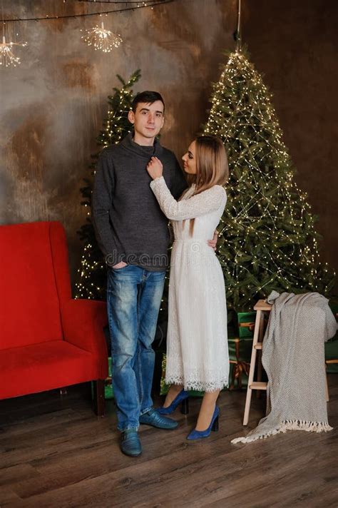 A Guy And A Girl Hug And Kiss Against The Background Of A Christmas