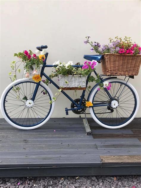 A Blue Bicycle With Flowers In The Basket Is Parked On A Wooden