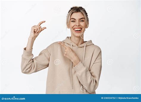 Portrait Of Happy Blond Woman Laughing Pointing At Pinching Fingers