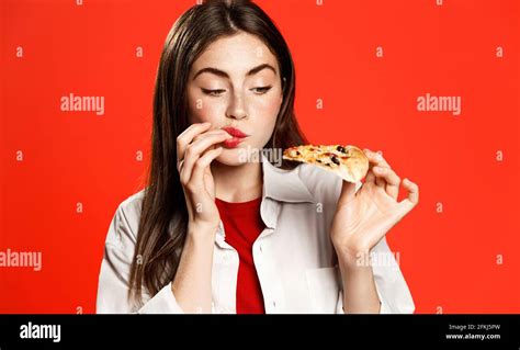 brunette girl licks fingers amazed by super good taste of pizza slice eating fast food delivery