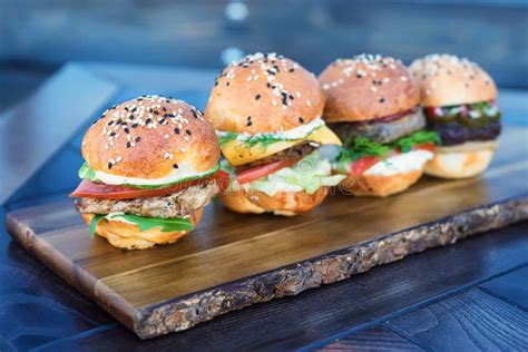 Four Burgers On Wooden Board In Restaurant Stock Photo Image Of