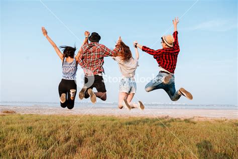 Back View Of Happy Excited Young People Holding Hands And Jumping In