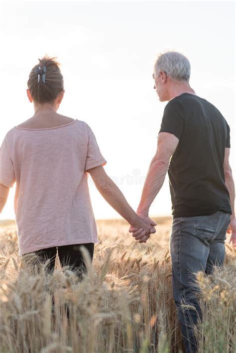 Couple Holding Hands In A Wheat Field At Sunset Sunlight Effect Stock