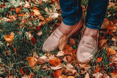 female legs in patent leather shoes on the autumn fallen leaves autumn concept stock image