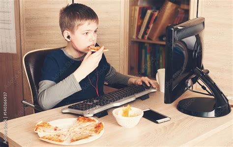 Kid Eating Pizza And Surfing On Internet Or Playing Video Games On Ps Boy In Headphones Eating