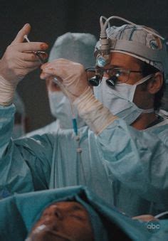 Two Doctors In Scrubs Are Performing Surgery On A Patient S Arm And Head