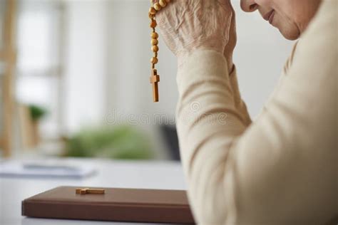 Senior Christian Woman Praying To God And Holding Rosary Beads Over The