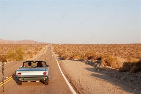 Couple Driving Convertible Car On Desert Highway Back View Stock Photo