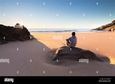 A Person Sits On A Beautiful Remote Beach In Australia And Watches A