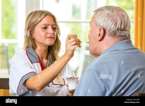 Elderly Care In A Nursing Home Nurse Helps An Elderly Man Eating His