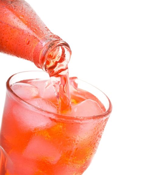 Premium Photo Pouring Red Soda Into Glass With Ice From Bottle