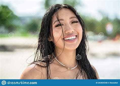 sland girl beautiful natural asian woman with wet hair and big toothy smile looking at the
