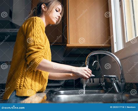 Beautiful Young Woman Washing A Coffee Cup In The Kitchen At Home Stock