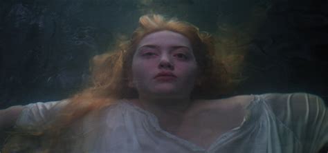 A Woman With Red Hair Is Floating In The Water And Looking At Something Off Camera