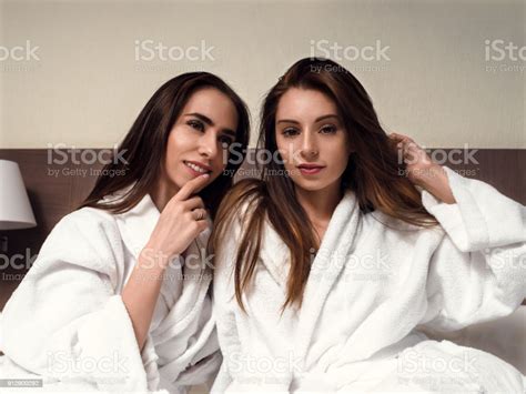 Two Brunettes In Dressing Gowns Are Lying On The Bed Stock Photo