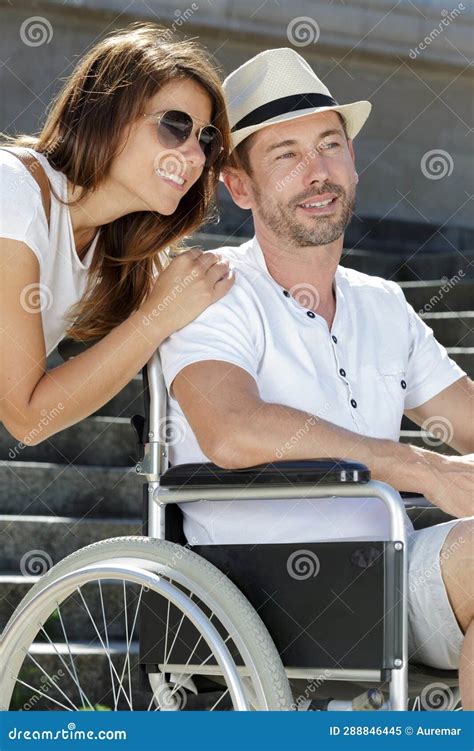 Woman Embracing Man In Wheelchair During Summer Holiday Stock Image