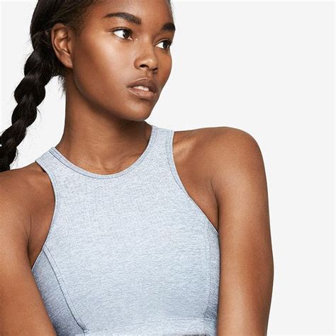 a woman with braids in her hair wearing a gray tank top and black pants