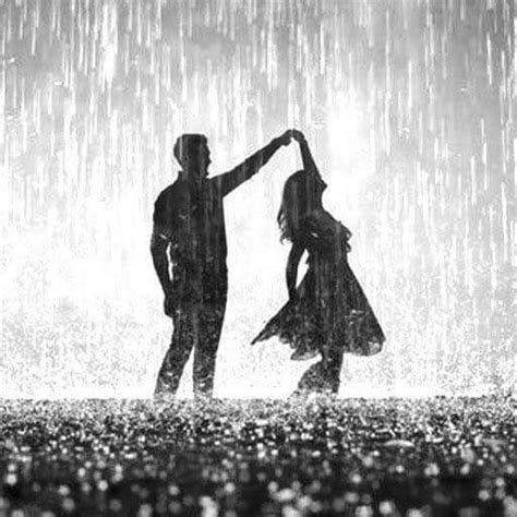 Two People Dancing In The Rain With An Umbrella Over Their Heads And