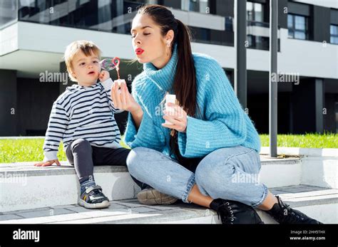 Playful Mother Blowing Soap Bubble By Son In City Stock Photo Alamy