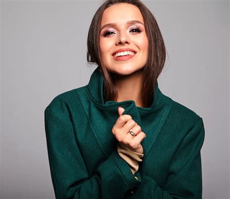 Lächelnde Süße Brünette Frau In Lässiger Grüner Jacke Auf Grau Kostenlose Foto